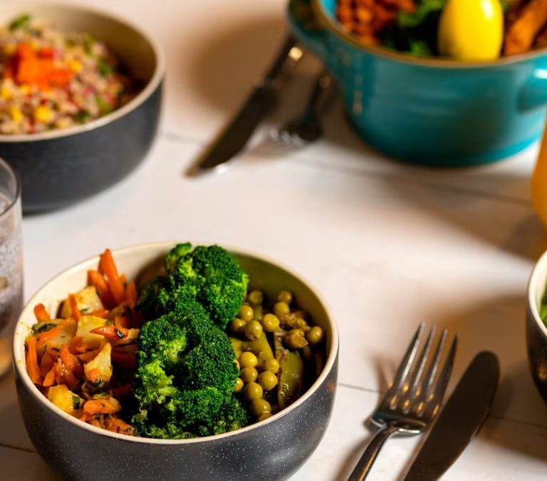 Delicious colorful bowls of salad and fresh beverages on a white table, perfect for healthy dining.